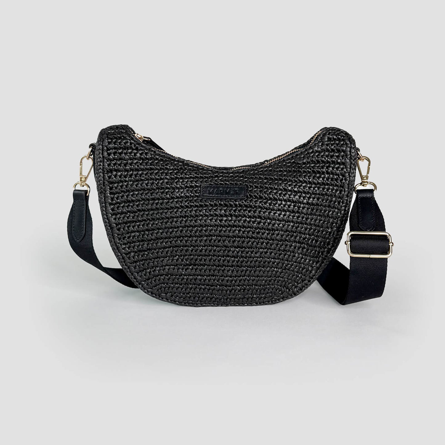 Black woven crocheted handbag with a strap on a light gray background