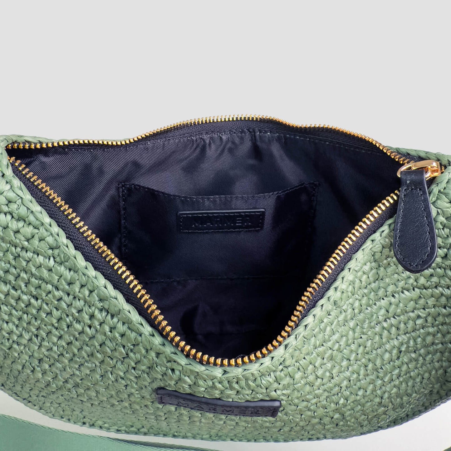 Green textured pouch with gold zipper on a light gray background