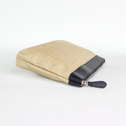 Beige pouch with black leather trim and black zipper on a white background