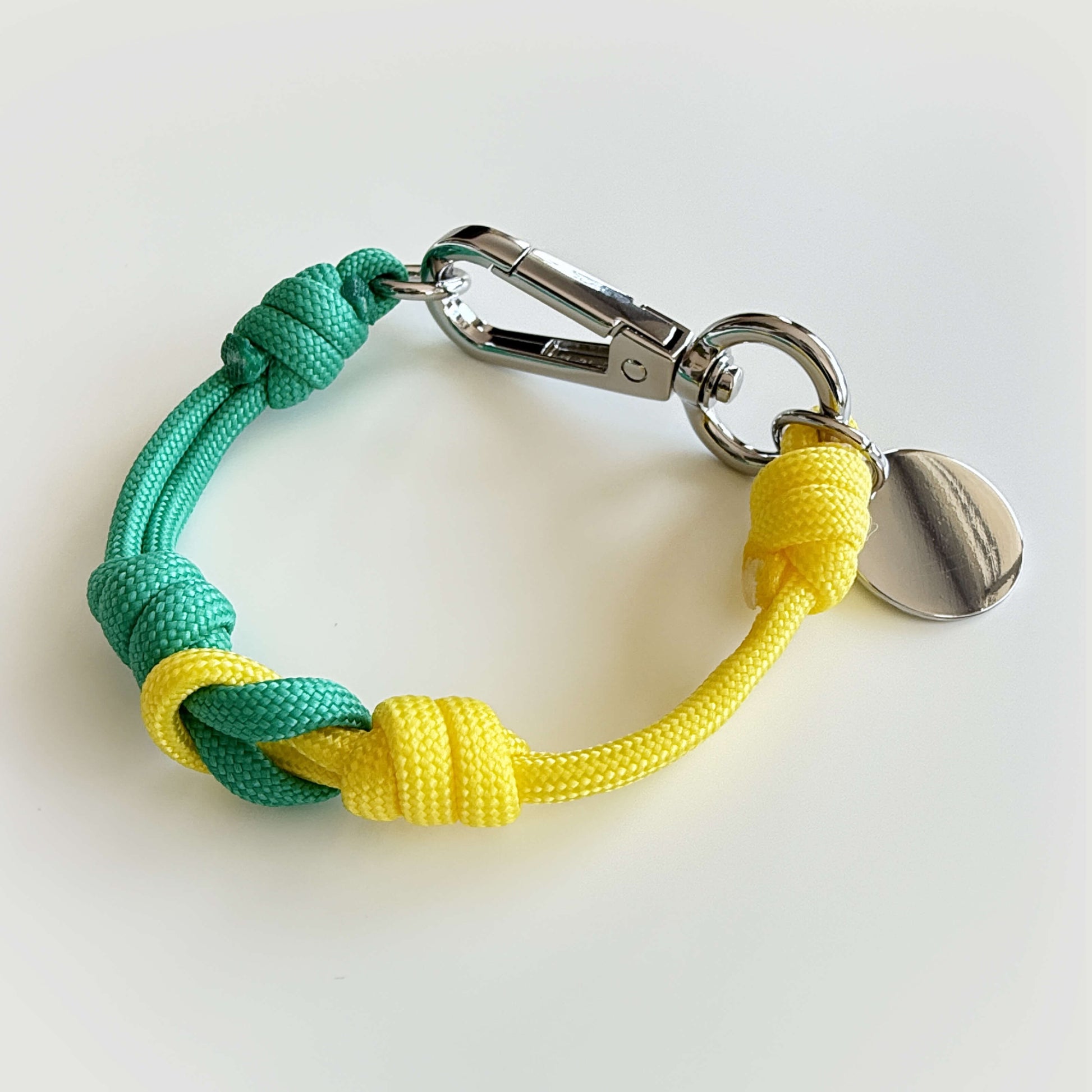 Mapo cord bracelet in beach color with metal clasp and tag.