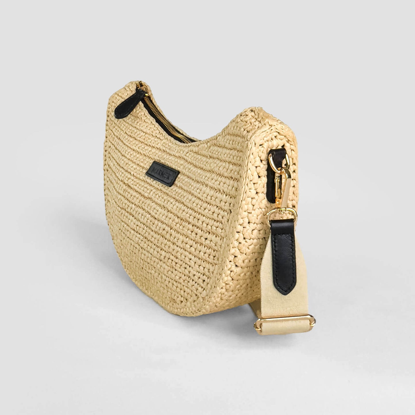 Beige woven handbag with black zipper on a light gray background