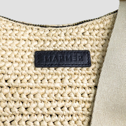 Close-up of a woven beige bag with a black label on a light gray background